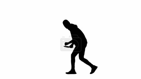 Téléchargez les photos : Silhouette noire de voleur sur fond blanc isolé. Un voleur en sweat à capuche et cagoule marche avec un couteau dans les mains, se préparant à commettre un crime. Vue latérale - en image libre de droit