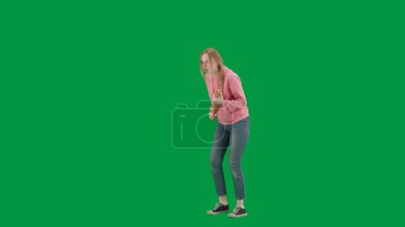 Photo for Robbery and criminal concept. Portrait of victim on chroma key green screen background. Young girl walking alone, scared face expression, holding baseball bat , looking around. Half turn - Royalty Free Image