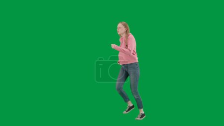 Photo for Robbery and criminal concept. Portrait of victim on chroma key green screen background. Young girl running, scared expression, looking around, running faster from danger. Half turn - Royalty Free Image