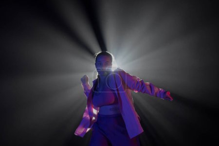 Photo for Girl in pink clothes dancing in dark studio with smoke and backlight. The dancer demonstrates elements of choreography in jazz funk style - Royalty Free Image