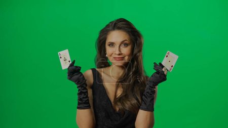 Photo for Casino and gambling commercial advertisement concept. Elegant female in studio on chroma key green screen background. Attractive woman in black dress with pair of ace cards looking at camera. - Royalty Free Image