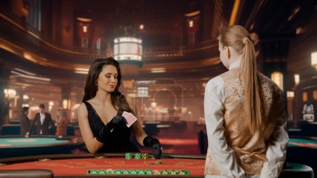 Photo for Elegant woman in black dress in casino. Attractive woman at blackjack poker table. Woman holding cards and betting with chips. Female croupier waiting for bet. Concept of casino and gambling - Royalty Free Image