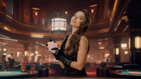 Photo for Chic woman in black dress at poker table for blackjack game in casino. Woman holding poker playing cards and looking at camera. The concept of casino and gambling - Royalty Free Image