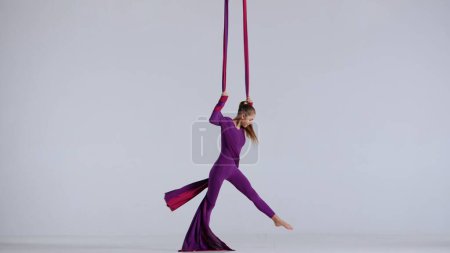 Photo for Modern choreography and acrobatics creative advertisement concept. Portrait of female acrobat isolated on white background in studio. Girl aerial dancer performing spinning element on air silk. - Royalty Free Image