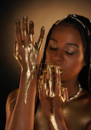 Téléchargez les photos : Portrait d'une femme afro-américaine avec des chaînes en or dans les cheveux. L'or liquide coule dans les bras des modèles. Gros plan. Le concept de beauté - en image libre de droit