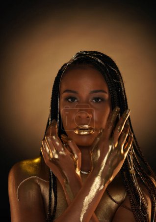 Téléchargez les photos : Portrait d'une femme afro-américaine avec des chaînes en or dans les cheveux. L'or liquide coule dans les bras des modèles. Gros plan. Le concept de beauté - en image libre de droit