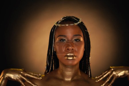 Téléchargez les photos : Portrait d'une femme afro-américaine avec des bijoux en or dans les cheveux. Les modèles bras, cou et épaules sont recouverts d'or liquide. Gros plan. Le concept de beauté - en image libre de droit