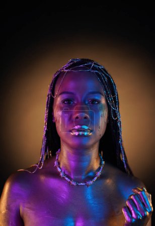 Foto de Mujer afroamericana con joyas de oro en el pelo. El cuerpo de los modelos cubiertos con oro líquido brilla en luz de neón violeta azul. Lágrimas doradas fluyen por las mejillas de las chicas. De cerca. - Imagen libre de derechos