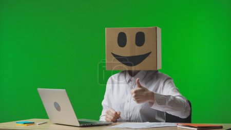 Photo for Woman in cardboard box with smiling emoji on her head on green background of studio. Employee gives a thumbs up. Business life. - Royalty Free Image