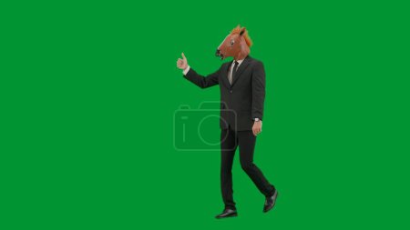 Téléchargez les photos : Homme en costume d'affaires avec masque de tête de cheval sur fond de studio vert. Homme d'affaires marchant, pointant les doigts dans la direction et montrant les pouces vers le haut geste. Concept de travail de bureau dur Demi tour - en image libre de droit