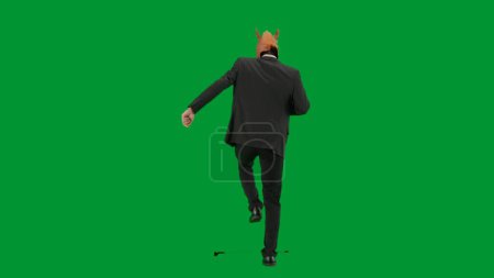 Téléchargez les photos : Homme en costume d'affaires avec masque de tête de cheval sur fond de studio vert. Homme d'affaires marchant, rebondissant et dansant. Concept de travail de bureau dur Vue arrière - en image libre de droit