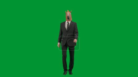 Téléchargez les photos : Homme en costume d'affaires avec masque de tête de cheval sur fond de studio vert. Homme d'affaires marchant à pied. Concept de travail de bureau dur - en image libre de droit