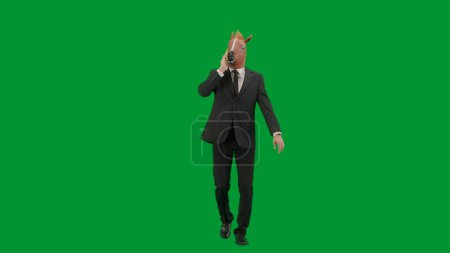 Téléchargez les photos : Homme en costume d'affaires avec masque de tête de cheval sur fond de studio vert. Homme d'affaires marchant et parlant sur smartphone. Concept de travail de bureau dur - en image libre de droit