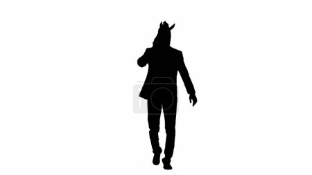 Téléchargez les photos : Silhouette noire de l'homme en costume d'affaires avec masque de tête de cheval sur fond de studio isolé blanc. Homme d'affaires marchant et parlant sur smartphone. Concept de travail de bureau dur - en image libre de droit