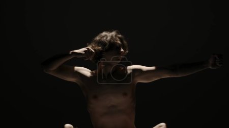 Photo for Body beauty and healthcare creative advertisement concept, Portrait of male model in studio on the black background under spotlight. Attractive man silhouette posing hands up at the camera. - Royalty Free Image