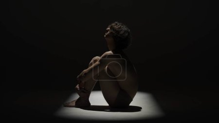 Photo for Body beauty and healthcare creative advertisement concept, Portrait of male model in studio on the black background under spotlight. Attractive man silhouette posing side profile at the camera. - Royalty Free Image