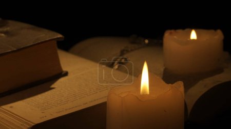 Photo for Historical and vintage objects creative advertisement concept. Studio shot of old retro hardcover book on background in warm light. Stack of old vintage books with candles and cross laying on table. - Royalty Free Image