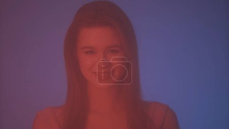 Photo for Beauty and cosmetology creative advertisement concept. Portrait of female in neon light behind the glass window in steam and mist. Girl with makeup and natural hairstyle smiling at camera. - Royalty Free Image