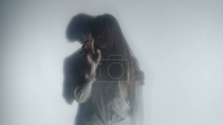 Photo for Silhouette of a man and a woman behind a frosted curtain or glass close up. A man approaches and puts his arm around the shoulders of a pensive and aloof woman drawing patterns on a frosted surface - Royalty Free Image