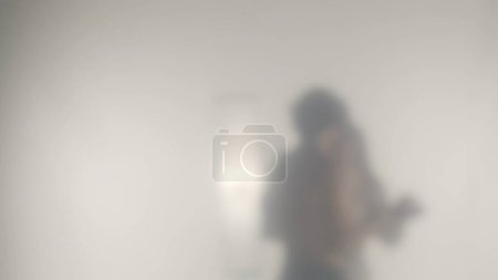 Photo for Silhouette of a couple embracing behind a frosted curtain or glass close up. A man with a naked torso and a woman tightly embracing. A meeting of lovers through time and space - Royalty Free Image