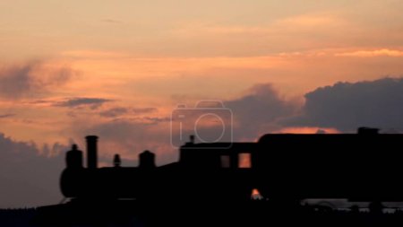 Photo for Transportation and industrial logistics creative advertisement concept. Shot of freight train on the railway over the land against sunset cloudy sky. Locomotive with barrels wagons crossing frame. - Royalty Free Image