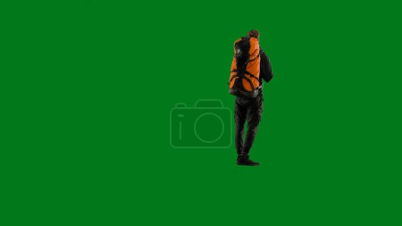 Photo for Back view of a male traveler with a large hiking backpack on his back. The man is standing full-length and enjoying the view. Hiker in studio on green screen - Royalty Free Image