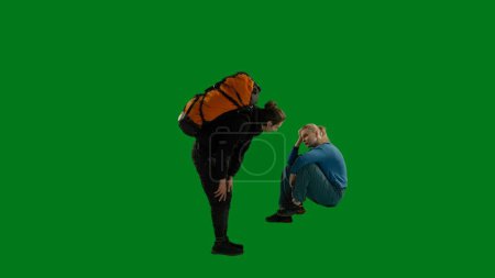 Photo for A caring male traveler encourages a weary crying woman to continue hiking. Hiking couple in studio on green screen. Caring and supportive in difficult situations. Family hiking - Royalty Free Image