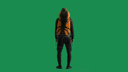 Téléchargez les photos : Vue arrière d'un voyageur masculin avec un grand sac à dos de randonnée sur le dos. L'homme est debout sur toute la longueur et profite de la vue. Randonneur en studio sur écran vert - en image libre de droit