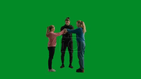 Photo for A group of hikers of three people put their hands together in a lock, laying a hand on each others arm. Tourist team in the studio on the green screen in full height. Travel concept, teamwork - Royalty Free Image