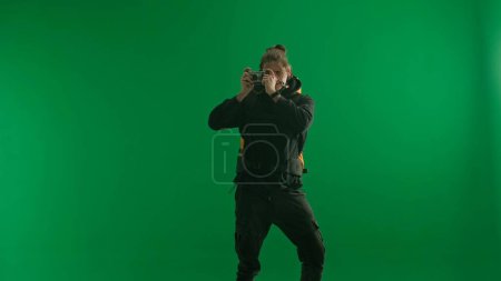 Photo for A male traveler takes pictures with a camera while hiking. Man hiker in studio on green screen. Concept of travel, active rest, hiking - Royalty Free Image