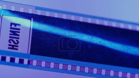 Foto de Una tira rayada de película fotográfica etiquetada Acabado sobre un fondo rosa en luz de neón azul de cerca - Imagen libre de derechos