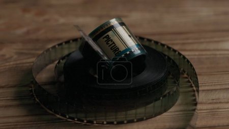 Téléchargez les photos : Torsadé en rouleaux de vieux négatifs de film blanc de 35 mm sur une table en bois dans le noir gros plan - en image libre de droit
