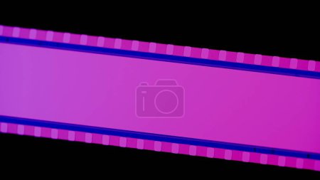Téléchargez les photos : Bande de film rose sur fond noir de près. Bande de cinéma sur fond noir. Cadre de diapositive de film 35mm. Cinéma ou cadres photo. Long, cadre de bande de film rétro. Espace de copie - en image libre de droit