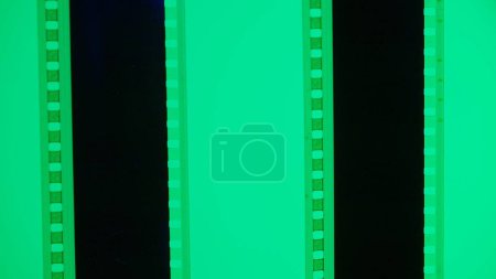 Foto de Dos tiras verticales de película sobre un fondo verde, de cerca. Marco de diapositiva de película de 35 mm. Marco de tira de película largo y retro. Copiar espacio - Imagen libre de derechos