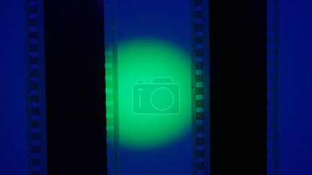 Téléchargez les photos : Deux bandes de film verticales sur fond bleu avec lumière circulaire verte, fermer. Cadre de diapositive de film 35mm. Long, cadre de bande de film rétro. Espace de copie - en image libre de droit