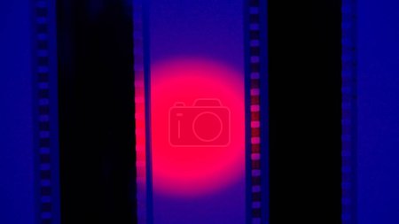 Téléchargez les photos : Deux bandes de film verticales sur fond bleu avec lumière circulaire rouge, fermer. Cadre de diapositive de film 35mm. Long, cadre de bande de film rétro. Espace de copie - en image libre de droit