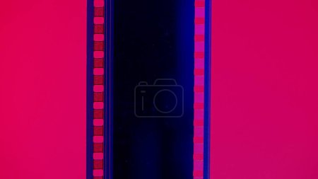 Foto de Tira de película vertical sobre fondo rojo, de cerca. Marco de diapositiva de película de 35 mm. Marco de tira de película largo y retro. Copiar espacio - Imagen libre de derechos