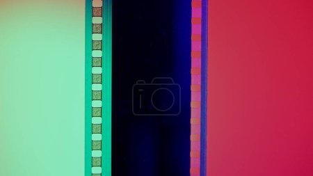 Foto de Tiras de película verticales sobre fondo rojo y verde, de cerca. Marco de diapositiva de película de 35 mm. Marco de tira de película largo y retro. Copiar espacio - Imagen libre de derechos