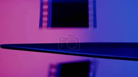 Foto de Tijeras corta una tira de película fotográfica sobre un fondo azul y rosa de cerca - Imagen libre de derechos