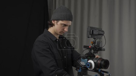Photo for The operator adjusts a professional video camera standing on a tripod close up. Behind the scenes of filming video production - Royalty Free Image