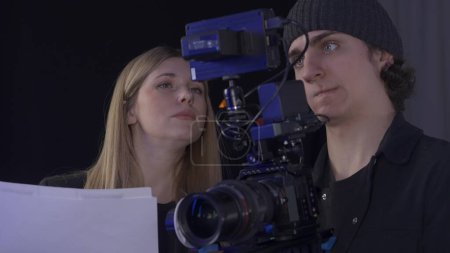 Foto de La tripulación detrás del escenario. Una productora y videógrafa ve imágenes en una cámara profesional, de cerca - Imagen libre de derechos