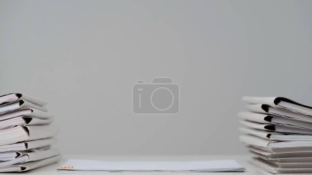 Photo for Workplace paperwork routine creative advertisement concept. Time lapse of paper sheets on white background. Stop motion animation of paper folders stacks and files business documents at the desk. - Royalty Free Image