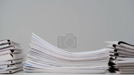 Photo for Workplace paperwork routine creative advertisement concept. Time lapse of paper sheets on white background. Stop motion animation of sheet folders stacks and business documents with clips at the desk. - Royalty Free Image