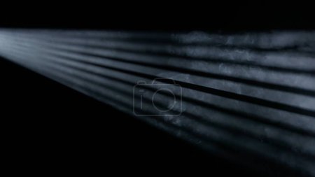 Photo for Professional stage equipment and lightning creative advertisement concept. Studio shot of projector haze jalousie effect isolated black background. Monochrome light rays shining from side with smoke. - Royalty Free Image
