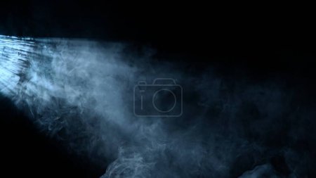 Foto de Equipo de escenario profesional y concepto de publicidad creativa relámpago. Captura de estudio del efecto de neblina del proyector aislado sobre fondo negro. Rayos de color blanco frío que brillan por los lados con humo. - Imagen libre de derechos