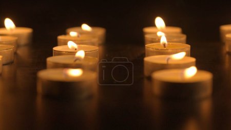 Photo for Burning candles. The candles burn against a black background and the flames move when the wind blows. The concept of a memorial day. Background for advertising and design projects - Royalty Free Image