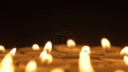 Téléchargez les photos : Des rangées de bougies allumées. Les bougies brûlent sur un fond noir. Le concept d'une journée commémorative. Contexte des projets de publicité et de design - en image libre de droit