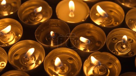 Photo for Many burning candles with melted wax. Soft warm light from the fire create a cozy atmosphere of peace and tranquility. Memorial day concept in church or temple, religion and ordinances - Royalty Free Image