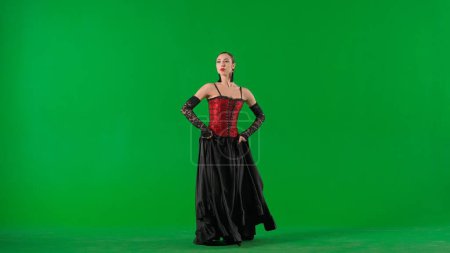 Photo for Modern choreography an dance. Woman dancer dancing on chroma key green screen. Female in flamenco style dress performs elegant spanish dance moves with her hands and body in the studio. - Royalty Free Image