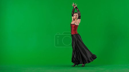 Téléchargez les photos : Chorégraphie moderne une danse. Femme danseuse dansant sur écran vert chroma key. Femme en robe de style flamenco effectue des mouvements élégants de danse espagnole avec ses mains et son corps dans le studio. - en image libre de droit